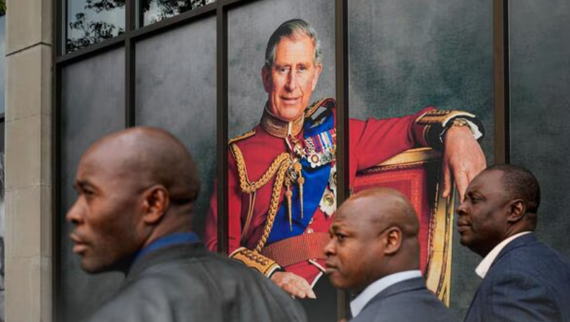 Men walk by a portrait of king charles iii, in london